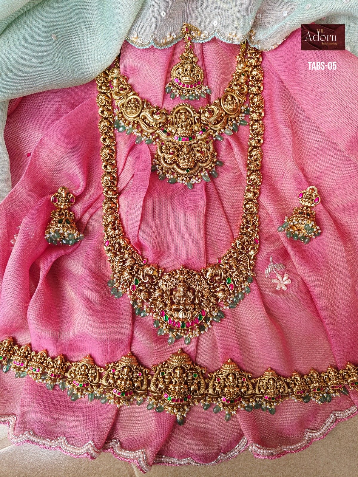 Lakshmi in Rose, A sculptural Lakshmi-led presentation photographed against rose silk, with green drops and vivid jewel-colour detailing.