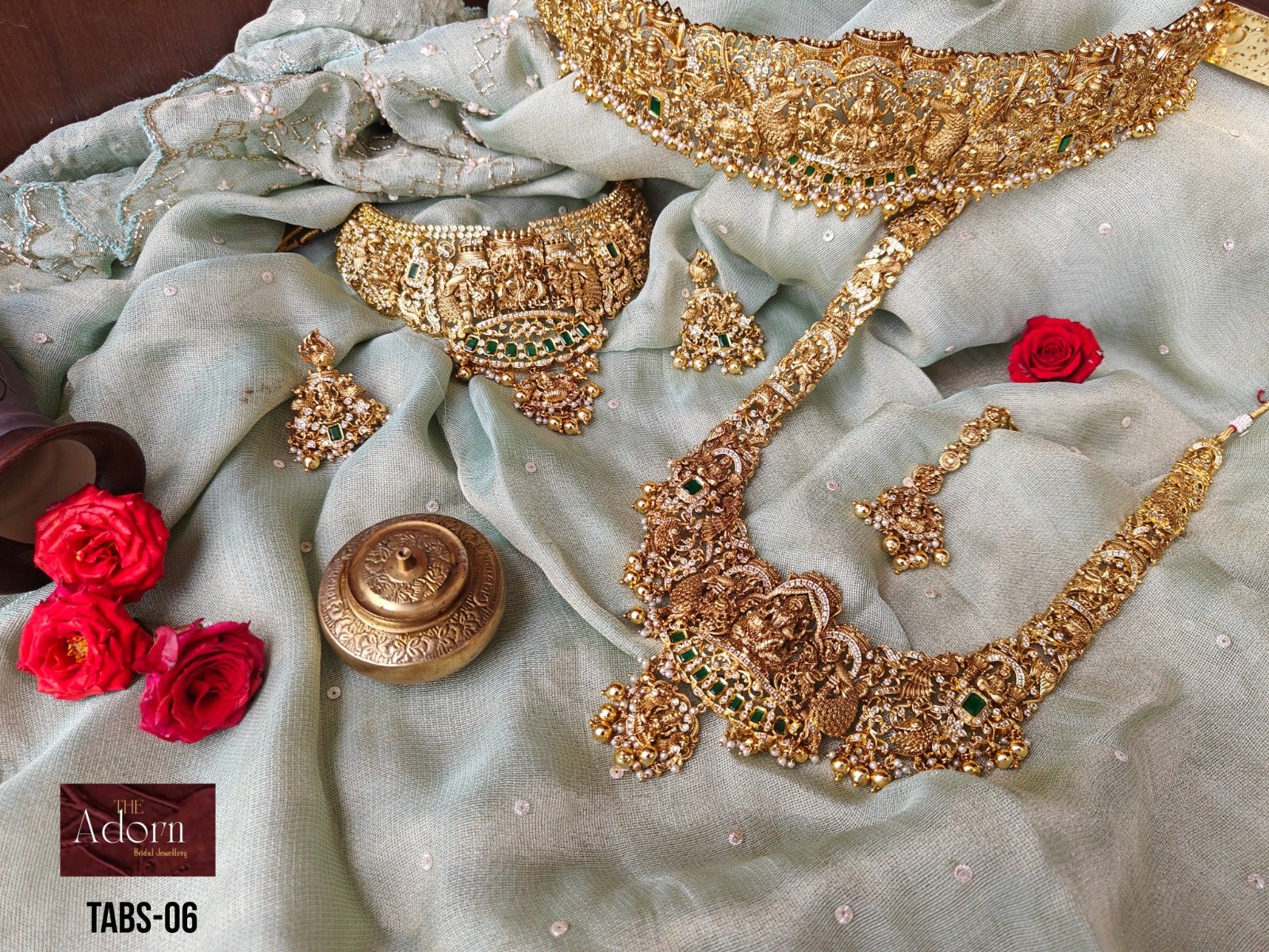 Gold-tone bridal jewellery arranged on pale blue silk with roses and ceremonial objects