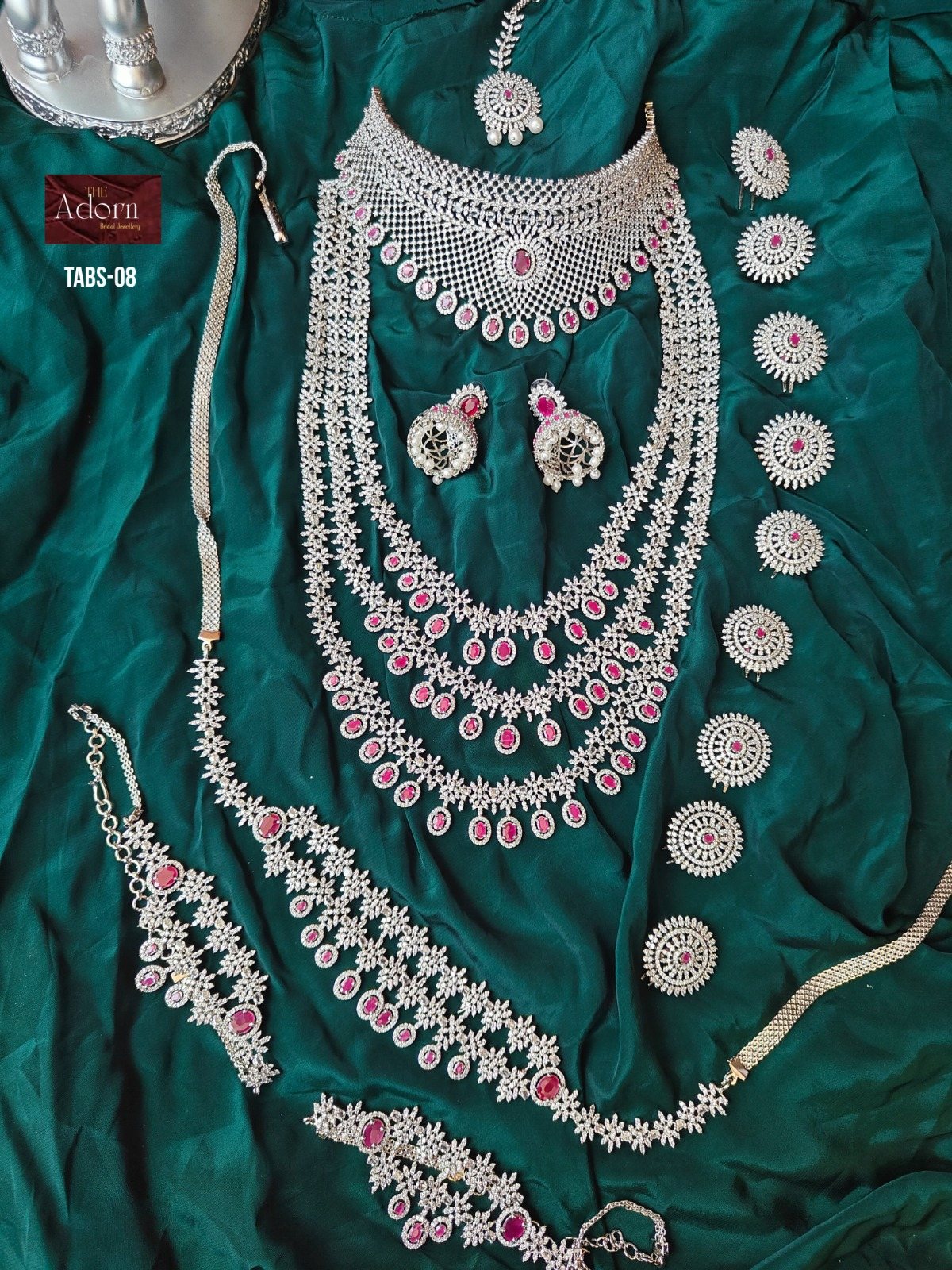 Ruby Constellation, A layered silver-tone presentation with repeated ruby-colour drops, bright floral links and a broad mesh-like neckline.