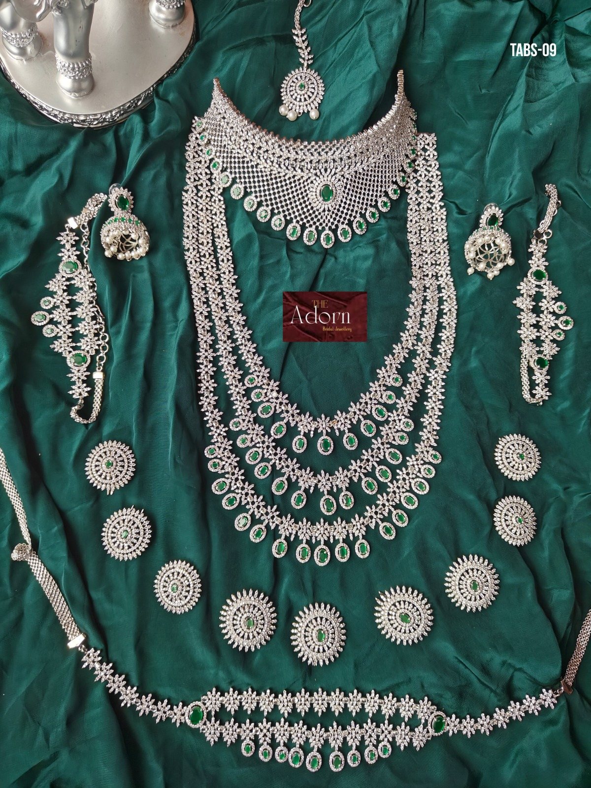 Emerald Constellation, An extensive silver-tone bridal presentation articulated by emerald-colour drops, circular accents and layered floral lines.